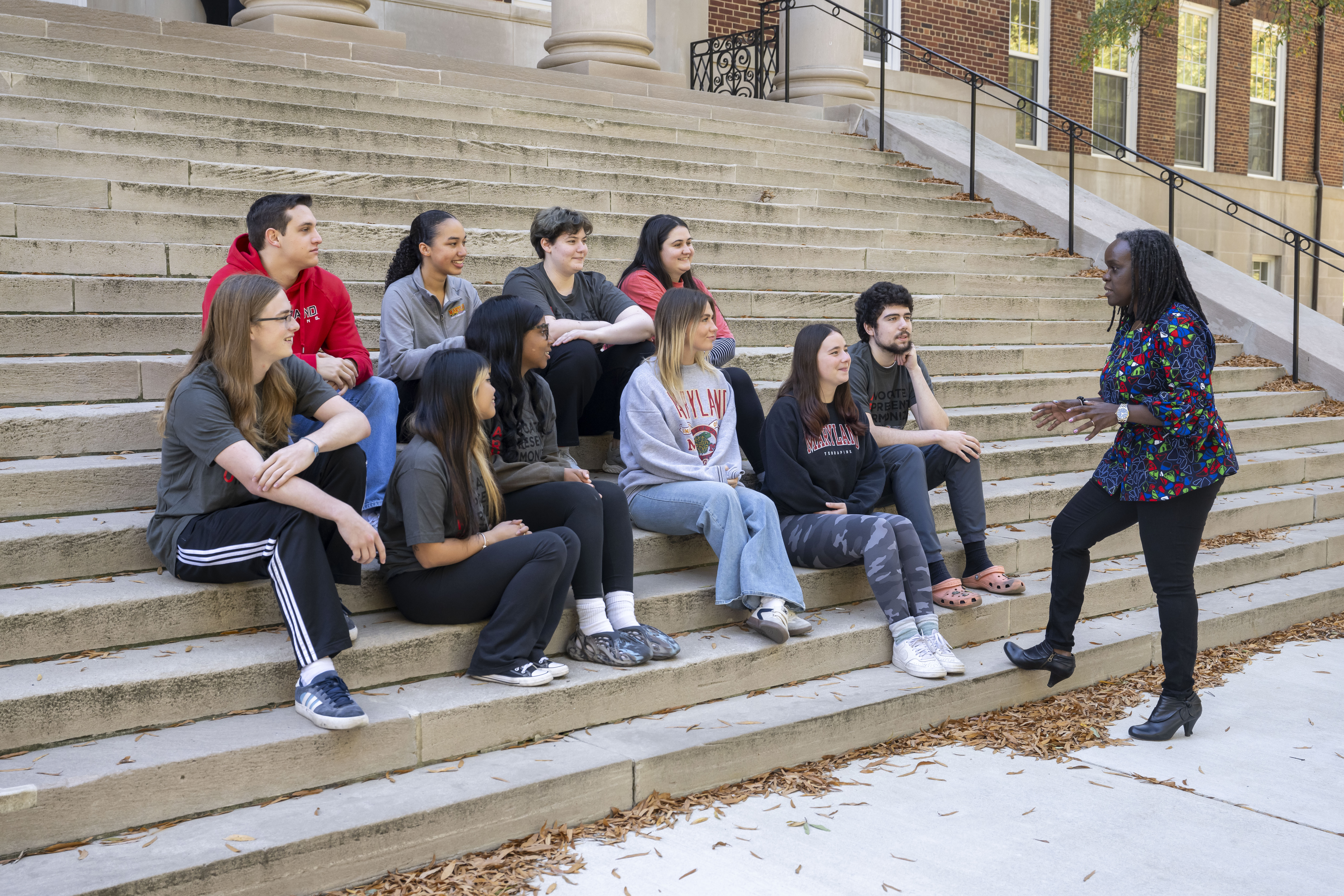 group of students sit on steps talking to Dean