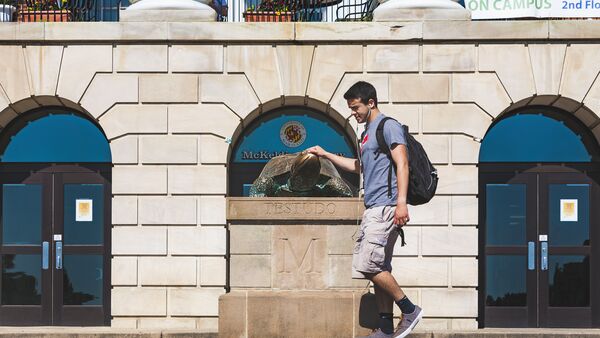 student touches testudo statue