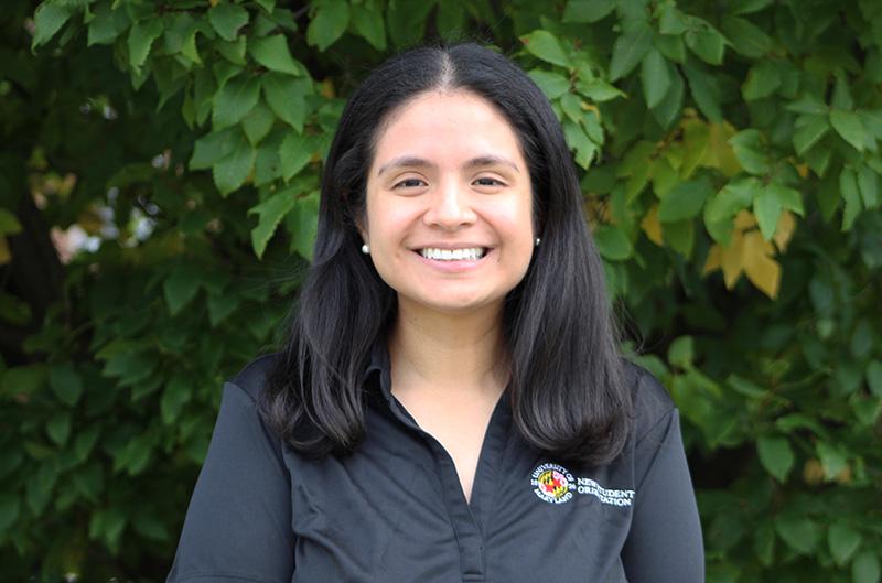 Ana is smiling at the camera wearing her black orientation polo