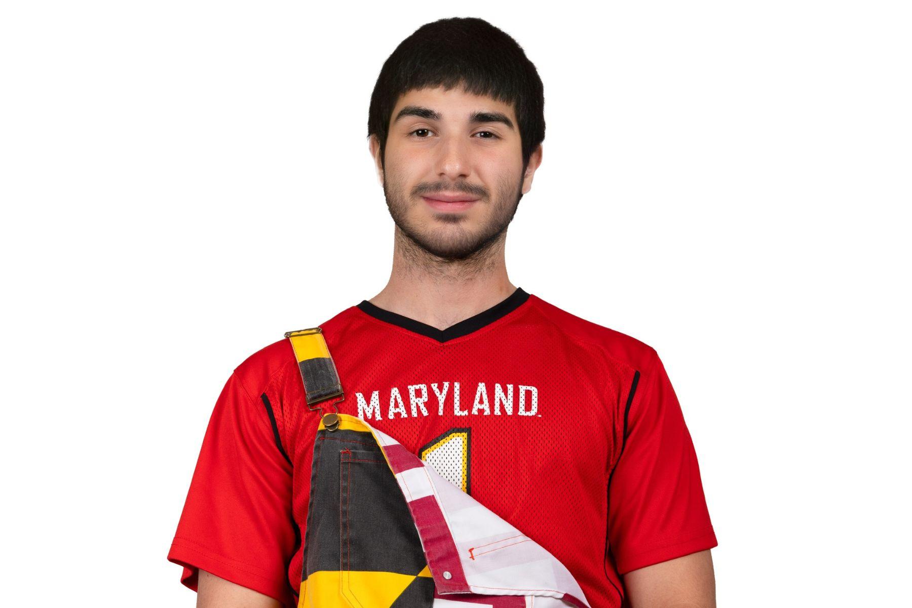 Emil is wearing a red Maryland jersey and is smiling at the camera