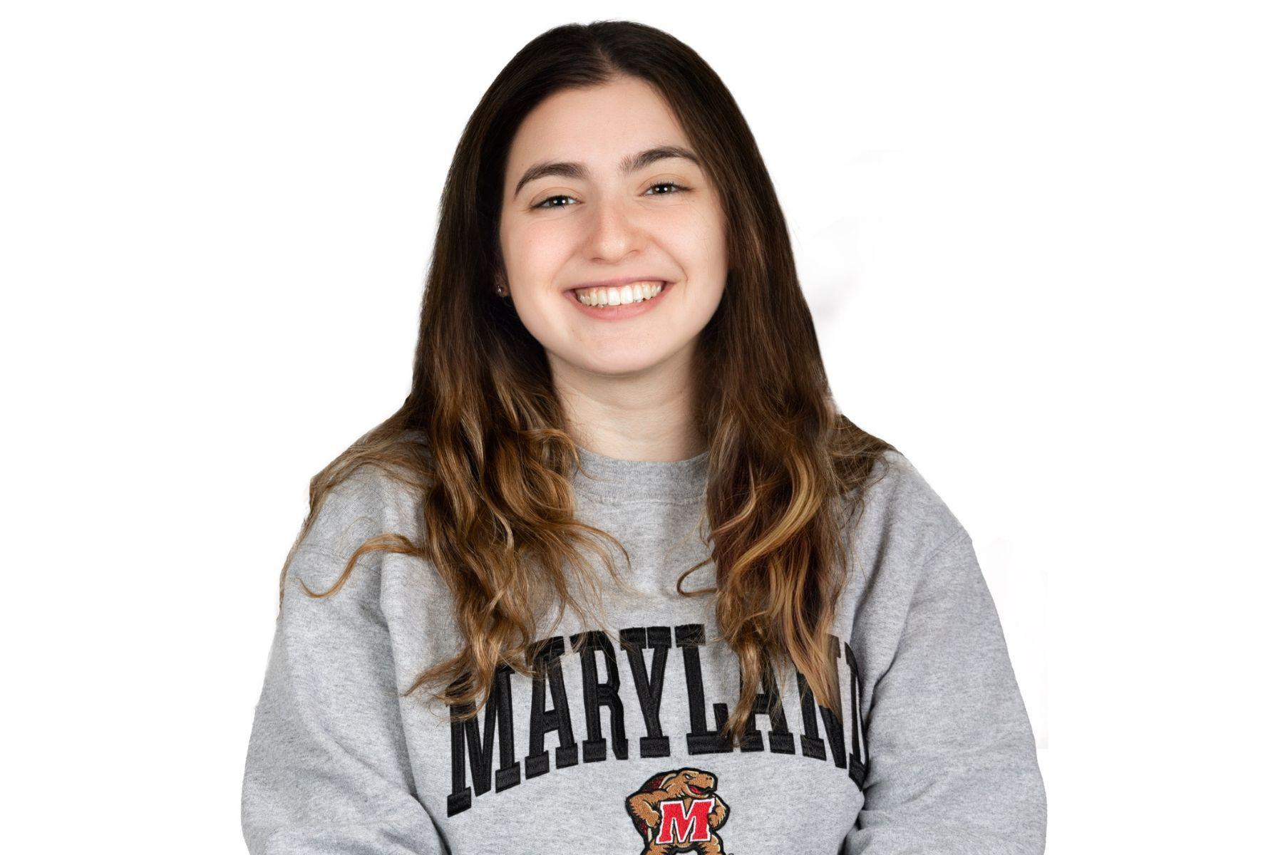 Julia is wearing a gray Maryland sweatshirt and is smiling at the camera