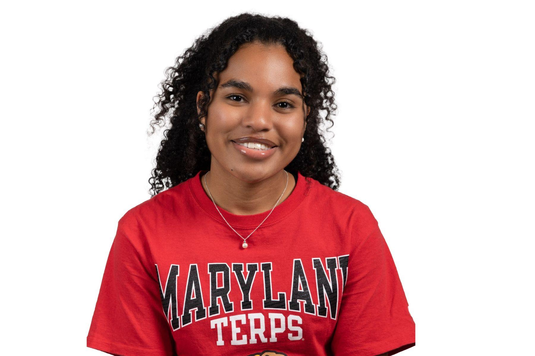Nadia is wearing a red Maryland shirt and smiling at the camera