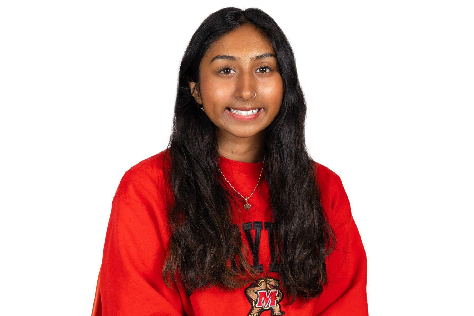 Saathvika is wearing a red Maryland sweatshirt and is smiling at the camera