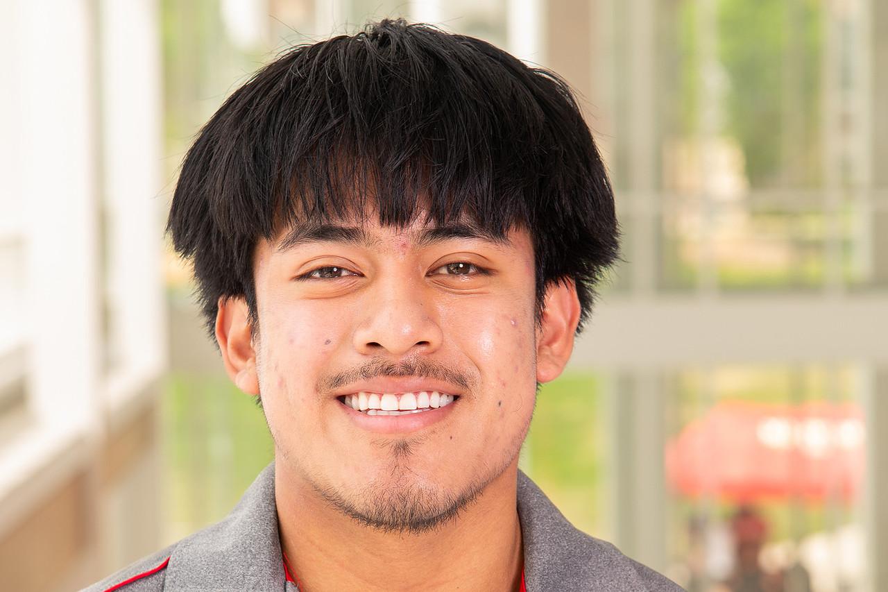 Transition Mentor Paolo Pena in a grey t-shirt with a red lines along the he shoulder and a folded collar