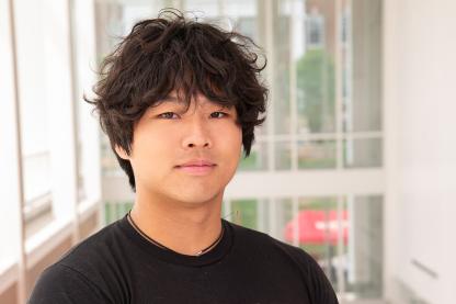 Transition Council Member Kyle Goh in a black Univeristy of Maryland t-shirt with a Red Maryland about the UMD flag in the globe shape. 